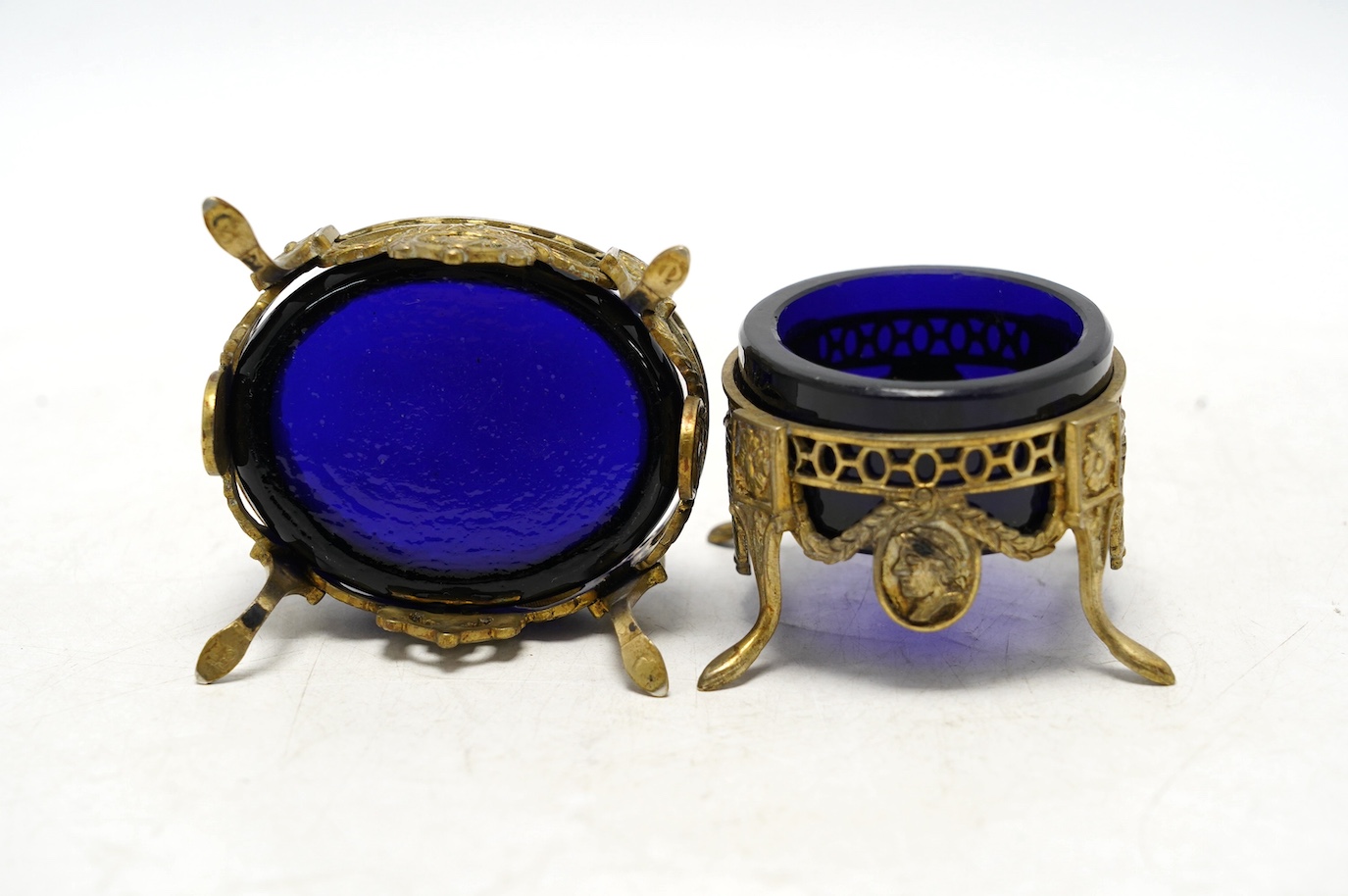 A pair of late 19th/early 20th century continental pierced gilt white metal oval salts, with blue glass liners, 69mm. Condition - fair